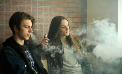 Two young people smoking e-cigarettes. Adobe